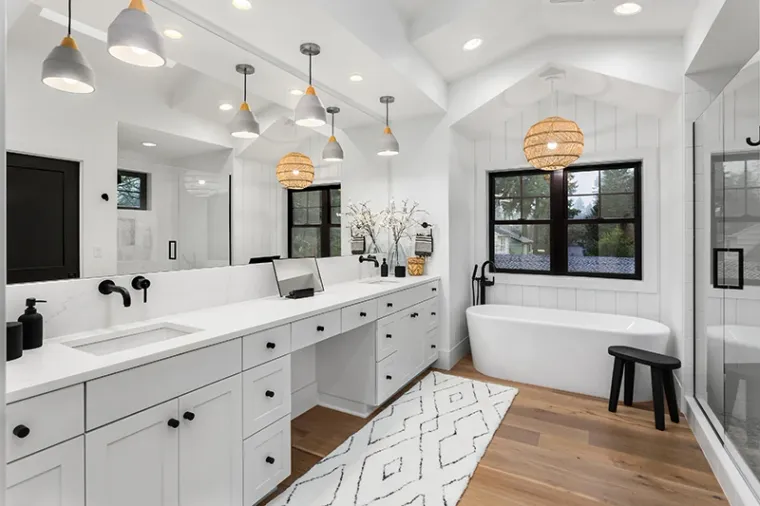 A bathroom with a clean, modern design. The space is bright and airy, with white tiles, a large mirror, and elegant fixtures.